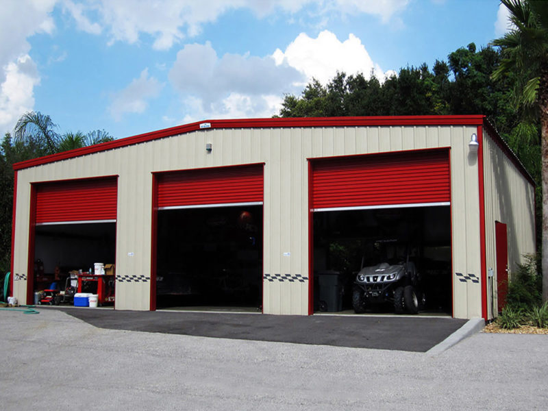 tan steel building garage with red trim, three garage doors